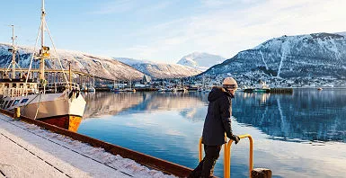 Teenage noy outdoors on winter day enjoying views of Tromso Norway