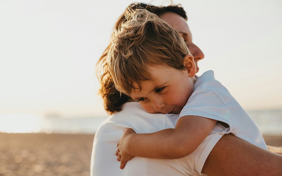 Câlin d'un fils avec sa maman sur une plage