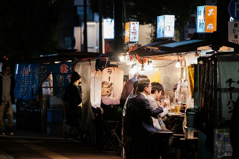 Groupe de personnes assises à un yatai à Fukuoka