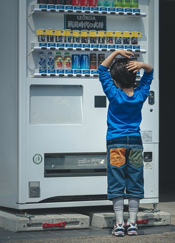 Enfant devant un distributeur de boissons au Japon
